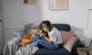 Vrouw knuffelt met een corgi op de bank