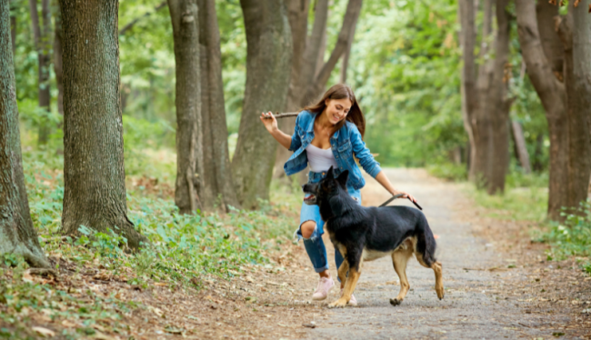 Een vrouw wandelt met een Duitse herder in het bos